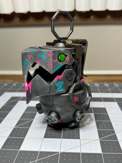 A 3D printed “Chompers” prop (grenade and bear trap combo) from League of Legends/Arcane. Has some neon “Jinx” style graffiti painted on it as well. (Other front side view)