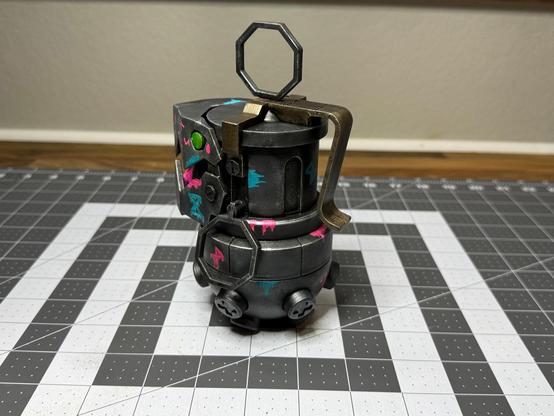 A 3D printed “Chompers” prop (grenade and bear trap combo) from League of Legends/Arcane. Has some neon “Jinx” style graffiti painted on it as well. (Rear side view)