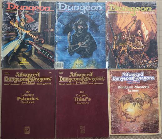 Dungeon Magazine #31: A paladin in plate mail with a blue tabard parries a sword and dagger that have no one wielding them.

Dungeon Magazine #19: The upper half of a very scary undead creature with red eyes and lots of sharp teeth wielding a scythe. It is materializing out of a rune on the floor of a stone keep.

Dungeon Magazine #53: An adventurer wearing leather armor and a hooded cloak wielding a sword and shield faces a skeleton with an axe. The floor is littered with human bones.


The Complete Psionics Handbook and the Complete Theif's Handbook for Advanced Dungeons and Dragons 2nd Edition: Both books are brown with gold lettering.

Dungeon Master's Screen: Two dragons fighting in mid-air.
