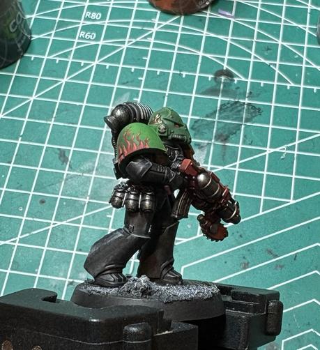 A Salamander Adherent for Warhammer Horus Heresy. His armor is black. Flames are painted on his right shoulder pauldron which is green. 