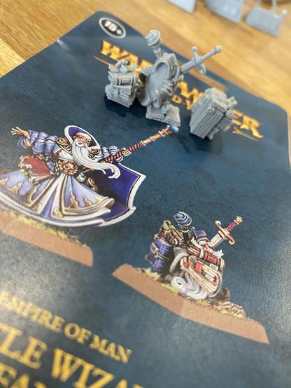 Unbuilt miniature sat on its instructions manual. The miniatures on the cover of the guide is a battle wizard and gnome familiar. 