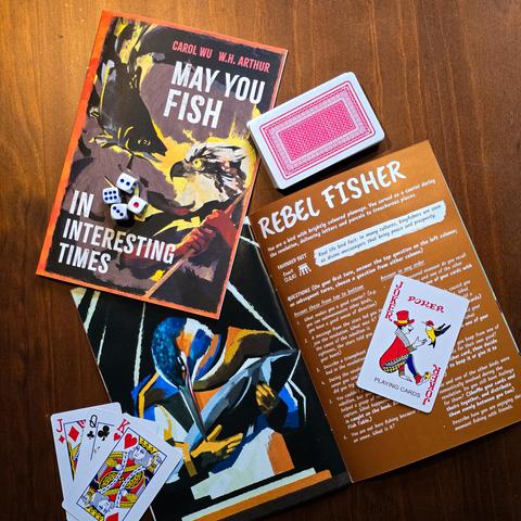 Photo of May You Fish in Interesting Times, featuring illustrations by Carol Wu. The cover art shows an osprey staring intensely at a fish, and the inner art showing a kingfisher holding a fish in their anthropomorphic arms.