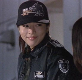 A photo from a more recent Godzilla movie -- though not that recent -- with a women Mechagodzilla pilot wearing a black JXSDF ballcap.