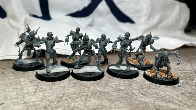 Eight undead blood bowl players assembled, all but one on a base. Three have gravel on the base, the others pools of glue still drying. 