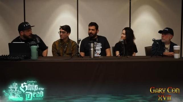 A still from the 'State of the OSR' panel at Garycon XVII.

5 panellists are sat in a line behind a long table. From right to left: Matt Finch, Kelsey Dion, Yochai Gal, Brad Kerr, and the designer of Pirate Borg whose name escapes me. 