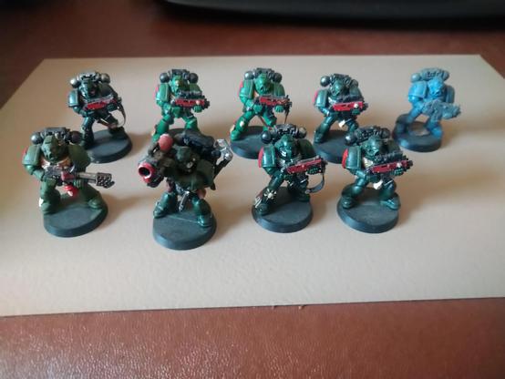 A squad of Dark Angel Space Marines in dark green armour. Red bolter guns.
One unpainted.