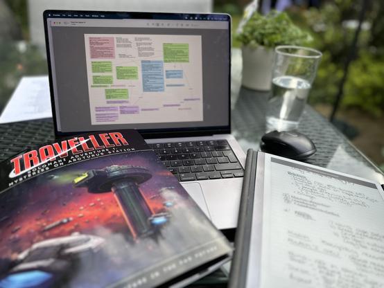 A garden table with a glass surface. From left to right: a copy of “Solomani Adventure 1: Mysteries on Arcturus Station” for the Traveller RPG, a MacBook Pro with a Scapple mind map of the investigation, and a mouse and reMarkable tablet with notes on the scenario. Portrait mode used to deliberately blur out spoilers. 