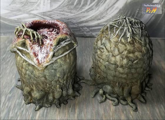 A pair of Alien eggs. One open with a facehugger emerging. high angle from the front.