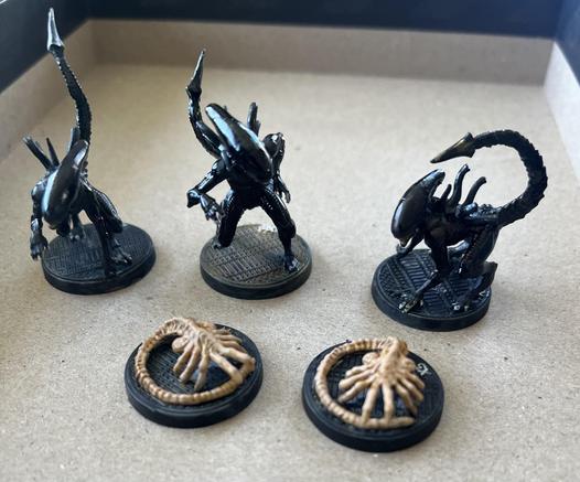 Painted xenomorph miniatures for the Alien roleplaying game. Two facehuggers in front, three xenomorphs behind.