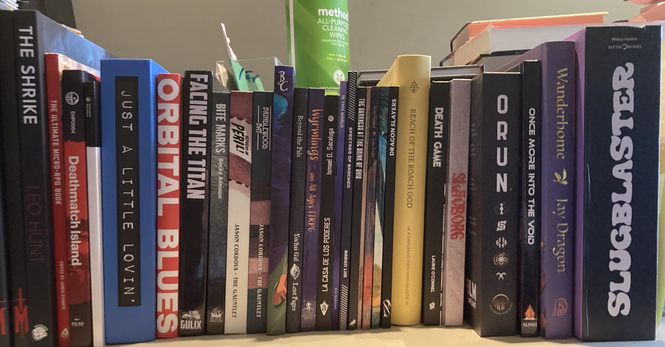 books on a shelf including orbital, facing the titan, orun, etc
