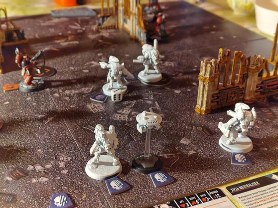 A kill team setup with ruins. Four primed but not painted stealth battlesuits and one marker drone advancing against two blood angels angels of death operatives.