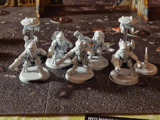Five XV26 stealth battlesuits and two drones. Models are primed white, but otherwise unpainted.