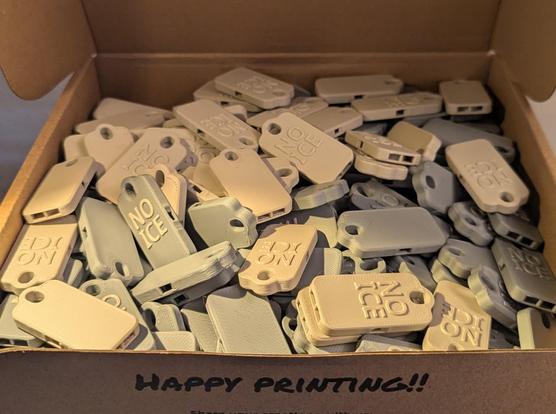 Box of 3d printed whistles with the words NO ICE visible on them.