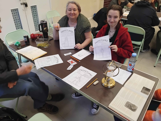 Showing off character sheets midway through a game of Puppetland, with an ornamental hourglass timing the story.