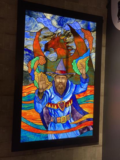 stained glass image of a wizard in front of a dragon