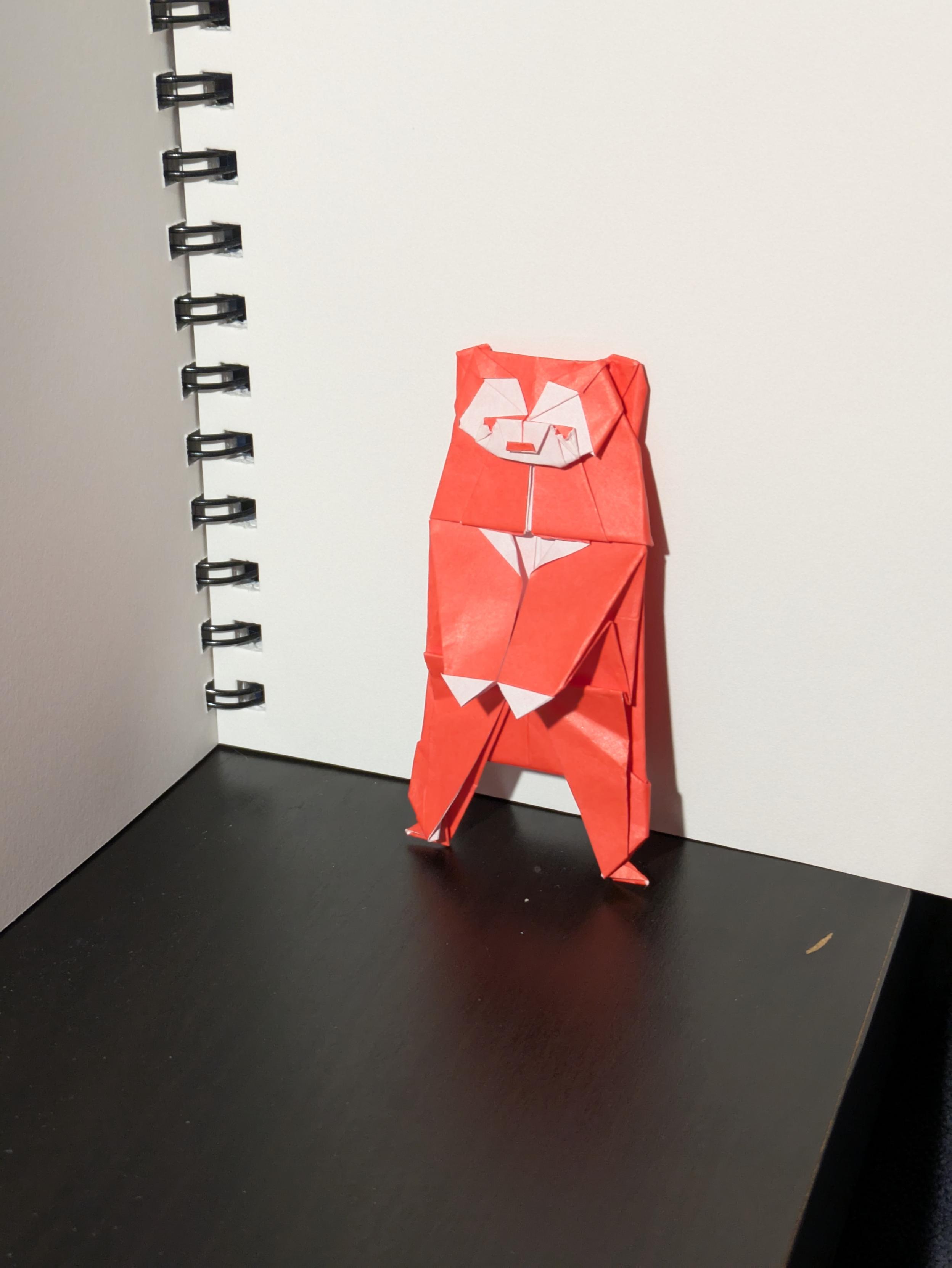 Origami sun bear standing upright in red paper