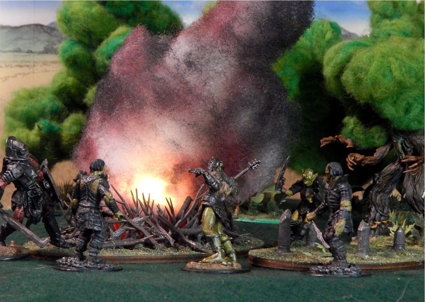 Photo of several orcs near a burning, smoking bonfire near a lush forest. 54mm painted orc figures near a bonfire made from cut-up model tree armatures around a flickering tea light topped with painted batting smoke. A flat terrain piece on the right shows chopped tree stumps. Trees in the background consist of wood/plastic trunks and green-dyed loosely felted roving, except for the angry resin ent figure on the right, advancing with menacing branch-claws on the destructive orcs.
