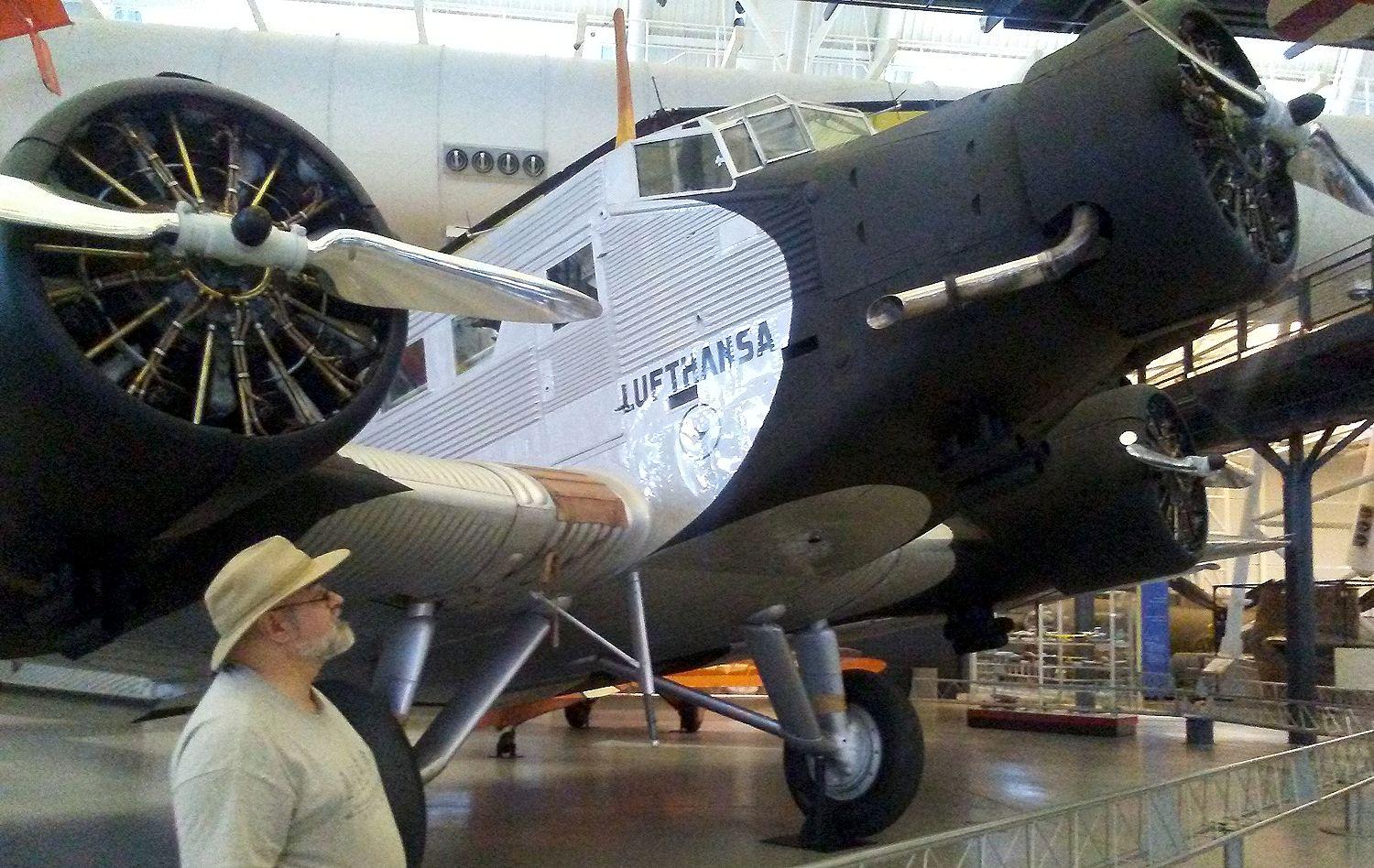 Doofy looking old white guy in beard, glasses, and a brimmed hat on the left looks up at a Junkers Ju 52 trimotor Lufthansa airliner, its engines in black paint, the Lufthansa logo beneath the squarish cockpit windows, with the corrugated metal fuselage behind. If you listen closely enough to the imaginary radio in my head you can hear through the crackling static: “Broadsword calling Danny Boy, Broadsword calling Danny Boy.”

https://airandspace.si.edu/collection-objects/junkers-ju52/nasm_A19880044000