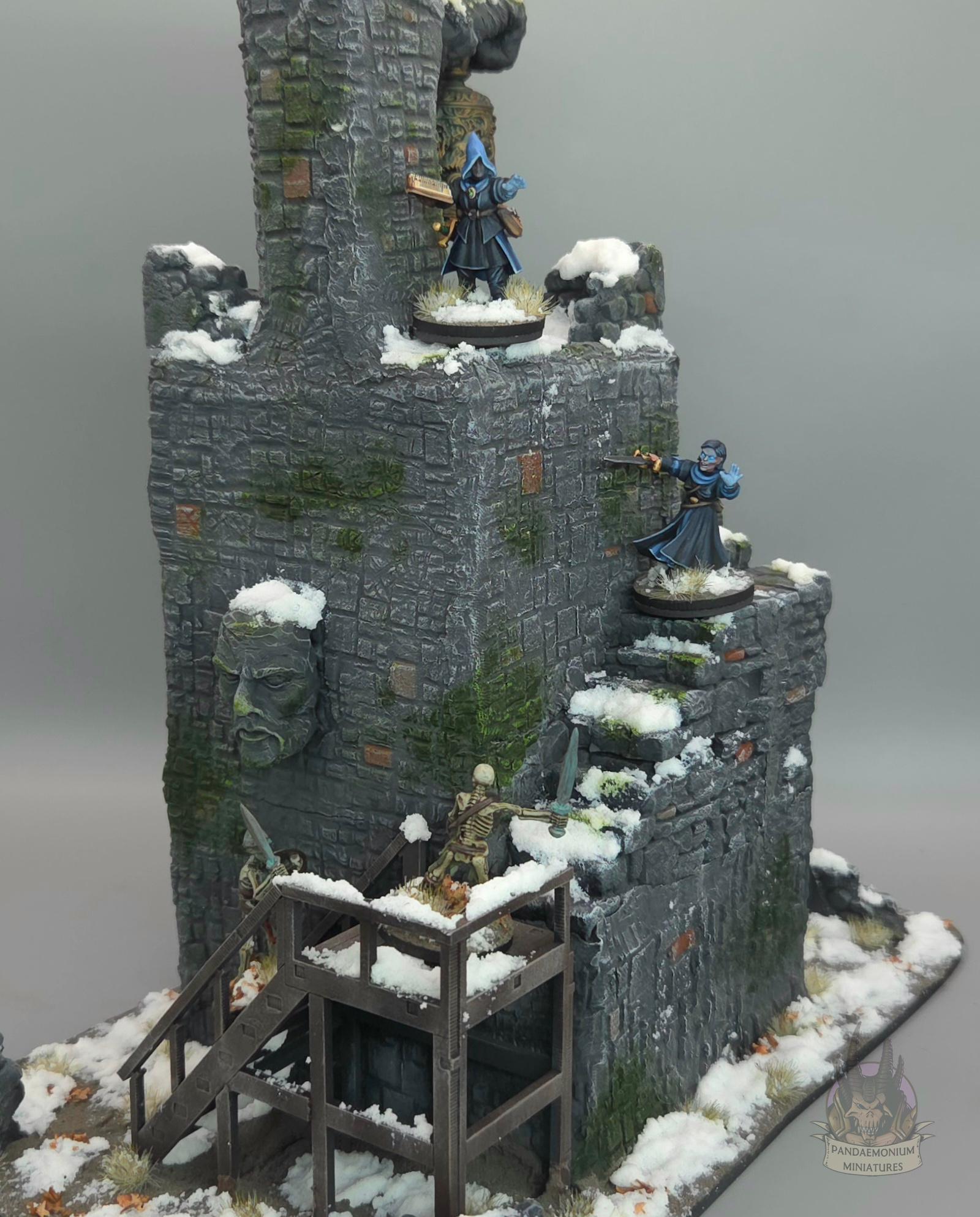 Wizards battle animated skeletons on the steps of a stone bell tower in a snowy setting with carved hand and face projecting from the walls. The first set of stairs is wooden, and the rest are stone, snaking up the outside of the tower. The bell itself is sculpted with a dragon design and clutched in a stone fist. A stone hand points ominously towards the stairs.