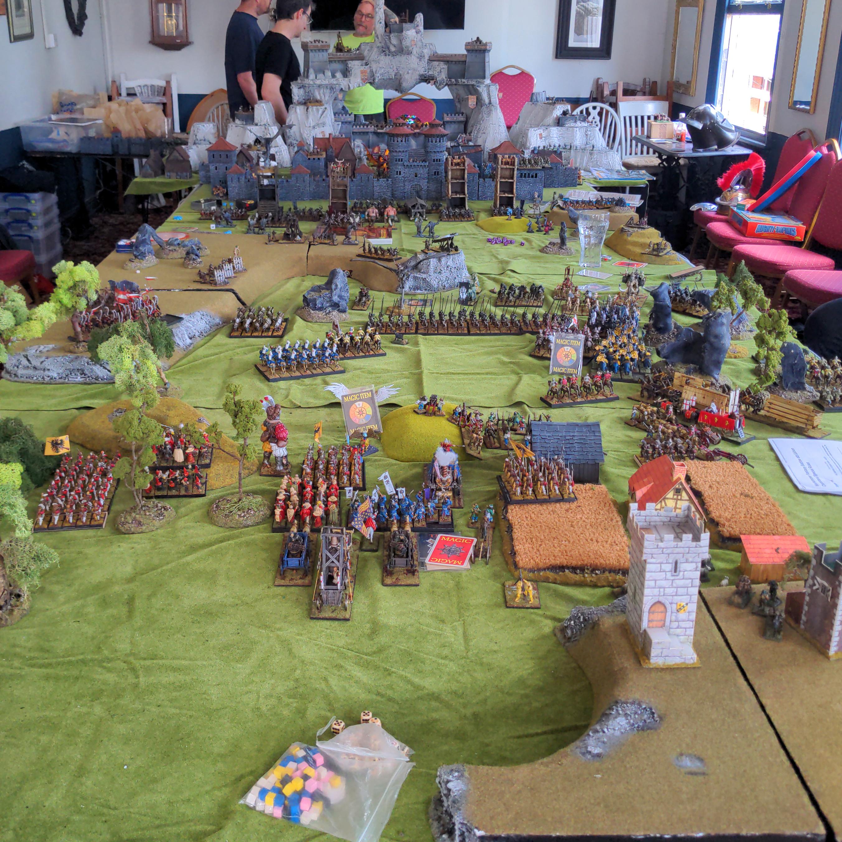 A huge gaming table laid out with thousands of miniatures, at the far end an imposing fortress dominates the battle field.