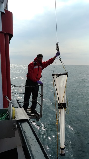 Photo of a plankton net being retrieved via a winch from a sampling stage on a ship by a technican.
Photo from DFO. Public Domain.