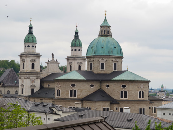 A cathedral with a large rotunda and two smaller towers, both with domed green copper roofs