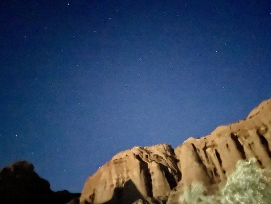 A somewhat blurred image of red-rock cliffs under a starry sky