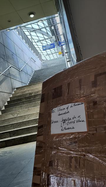 Großes Paket vor einer Treppe zum Bahnsteig