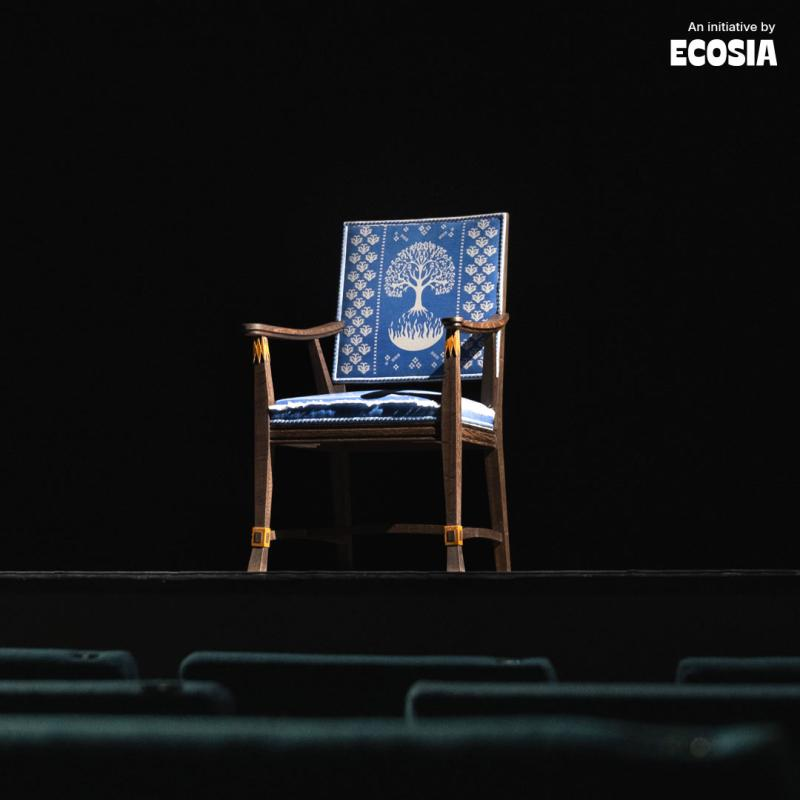 Leerer Stuhl mit blauem Bezug und einem Muster des Nobelpreises vor schwarzem Hintergrund