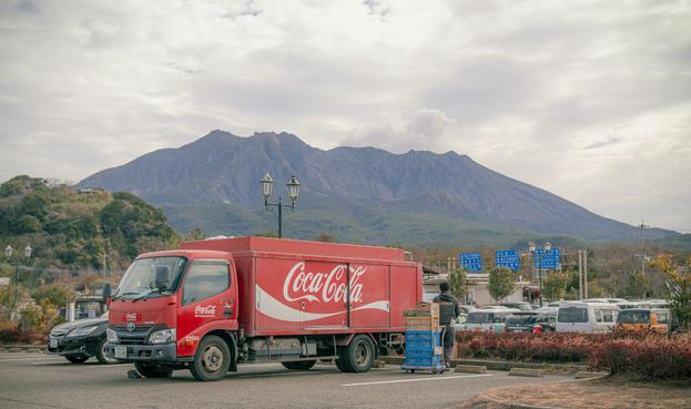 Parkender Coca Cola Laster vor Sakurajima Vulkan