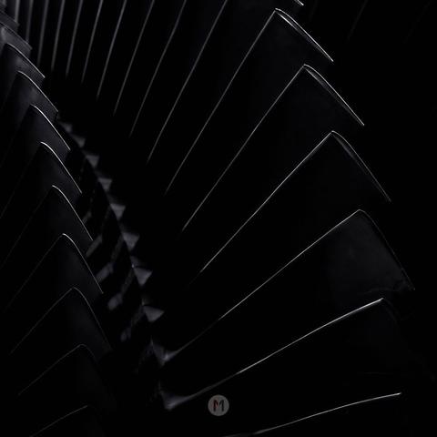 This image presents a close-up, abstract view of a series of sharp, angled metallic blades, likely part of a turbine or similar mechanical component. The blades are arranged in a repeating pattern, creating a sense of depth and rhythm.

Subject: Focuses on the repeating pattern of metallic blades.
Composition: Close-up, abstract, emphasizing lines and shapes.
Lighting: Dark and dramatic, with highlights emphasizing the edges of the blades.
Color: Primarily monochromatic, dominated by shades of black and gray.
Texture: Suggests a smooth, metallic surface with sharp edges.
Style: Minimalist, industrial, and potentially architectural.

Abstract Art: The repeating patterns and strong lines create a visually compelling abstract composition.
Overall, the image is striking in its simplicity and dramatic use of light and shadow, highlighting the beauty and complexity of industrial design.