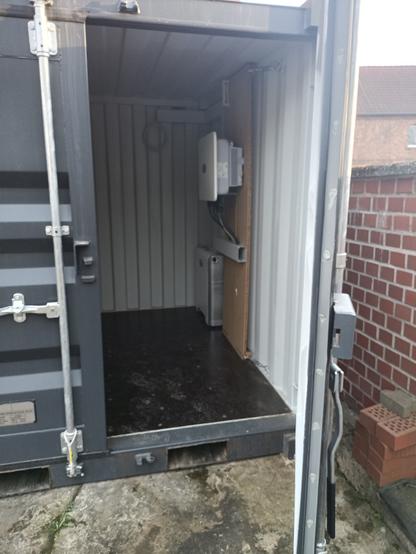 Ein geöffneter Container in dem ein Wechselrichter und ein Stromspeicher installiert ist.