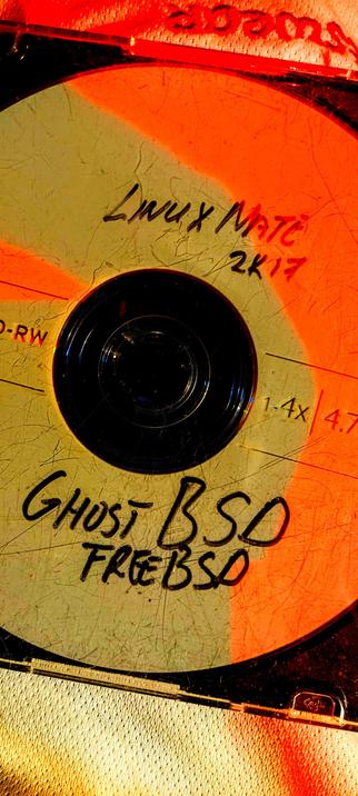 The photograph shows a DVD-rw with a yellow and red 🍒 color scheme. The DVD is labeled with handwritten text. At  top, it reads "Linux MATE 2K17," and at the bottom, it says "GHOST BSD FREEBSD." The DVD is a rewritable type, as indicated by the "DVD-RW" marking. The disc also has "1.4X" and "4.7" printed on it, likely referring to the disc's speed and capacity. The DVD is encased in a clear plastic holder, and the background has a red hue, possibly from lighting. The DVD shows signs of wear, with visible scratches and scuffs.

 Ovis2-8B

🌱 Energy used: 0.186 Wh