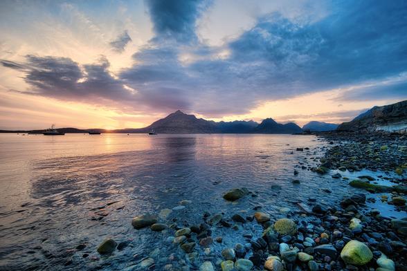 An image of a coastline with hills in the distance at sunset. Isle of Skye, Scotland
