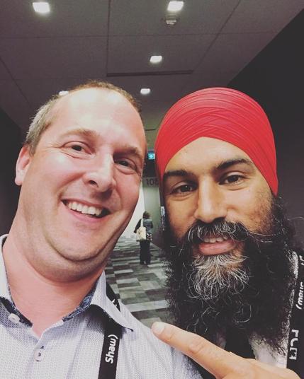 A selfie of myself and Jagmeet Singh on June 2, 2018 at the Federation of Canadian Municipalities Conference in Halifax.  I was just randomly walking down the corridor and Jagmeet was headed out of the building after a presentation. He had just been elected NDP leader earlier that Spring. I am wearing a light blue collared shirt and he is wearing a black suit with a red turban.