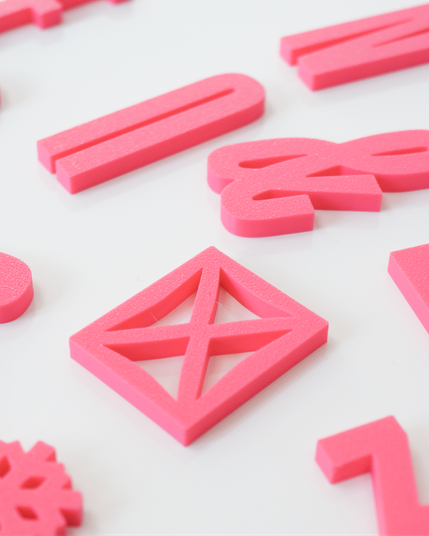 Closeup of pink Alphabet Magnets, in the form of the Rainer typeface