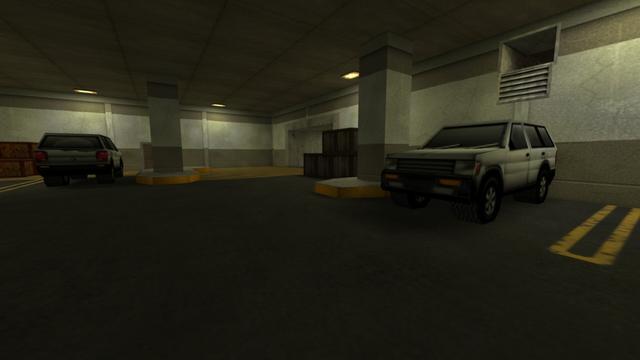 In this picture you can see the view from in front of the stairs from the last picture of the previous photo series. From left to right you can see two light wooden boxes, the second white SUV, a pillar where behind a wooden box to the left of the column is visible, an entrance / exit, three darker wooden boxes, another column, the first white SUV and where above it is an open ventilation shaft. Furthermore, you can see three yellow-lit lamps on the ceiling. This is on the map cs_siege in the game Counter-Strike 1.6.