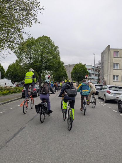 Le cortège, vu de dos, dans lequel on voit, au premier plan, cinq cyclistes dont un tallbike.