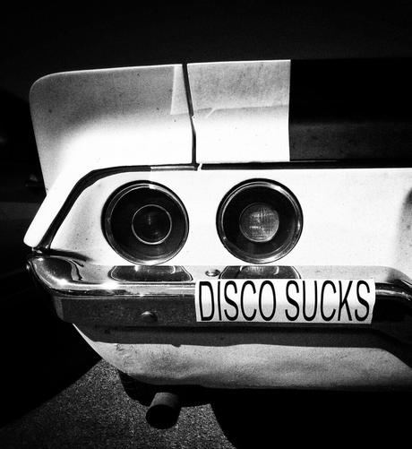 A black and white photo showing a view of the left rear section of a Camaro with a number sticker that reads "Disco Sucks".