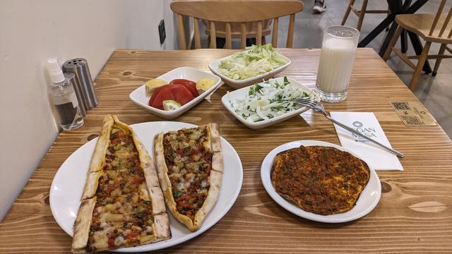 A restaurant table with Pide, Ayran and Salat.