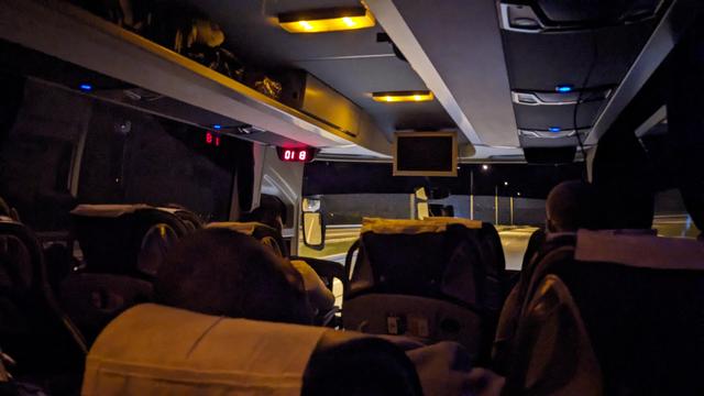 Interior of a bus at night. The bus is traveling on a highway and the lights are dimmed.