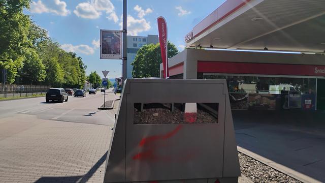 Es ist vor einer Tankstelle ein Tempoblitzer zu sehen.  Die Form und Farbe der Radarfalle ähnelt einer Panzersperre..