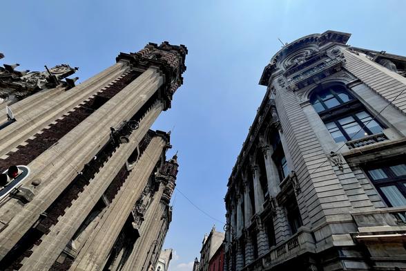 A photo of two buildings, a church with a classic style from the 1600s, and a neoclassical building, from the 1800s, taken from a lower point, having the building perspectives meeting at the top