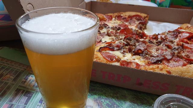 a glass of beer and some pizza.