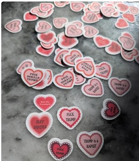 Pink and red heart shaped vinyl stickers with the anti-Trump messages listed.