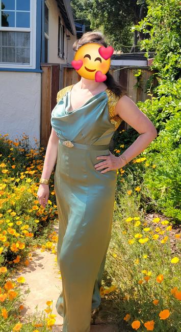 A sage green silk dress with a cowel neckline and heavily beaded shoulders. The dress has a narrow belt, with a gold rhinestone belt buckle.