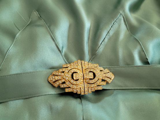 A close up of the belt buckle and belt.  There are two triangles of fabric above the belt, top stitched.