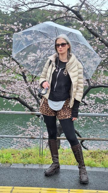 Katherine poses under a cherry blossom tree along the Chidorigafuchi Moat on a rainy day in Tokyo. She wears Xover0 jewelry, vintage leopard print shorts, Herno jacket, Rick Owens hoodie, and Trippen boots.