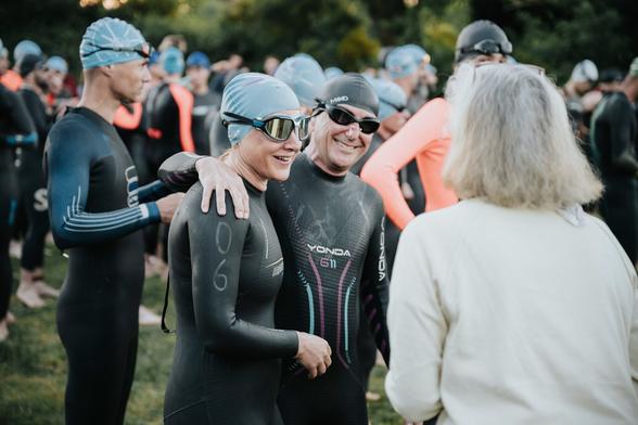 Des personnes souriantes habillées en tenues de plongée, avec des bonnets et lunettes de natation.