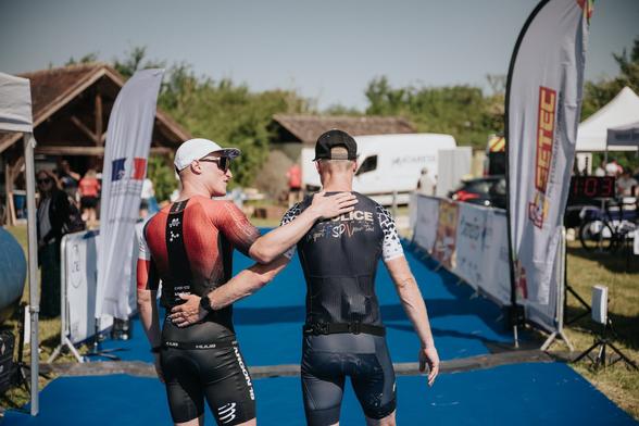 Deux hommes de dos en tenue de cycliste s'encouragent sur un parcours de course.